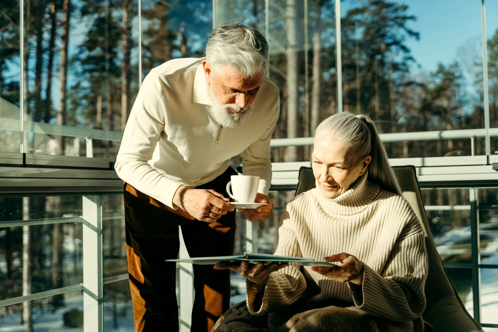A senior couple looks together at a tablet by a sunlit window, reviewing their day