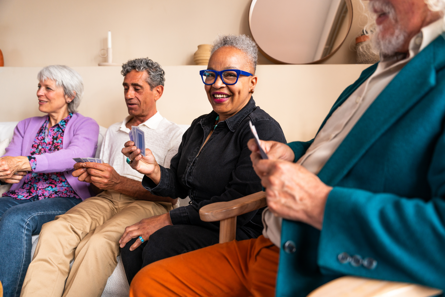 Four older adults enjoying a card game together, laughing and connecting