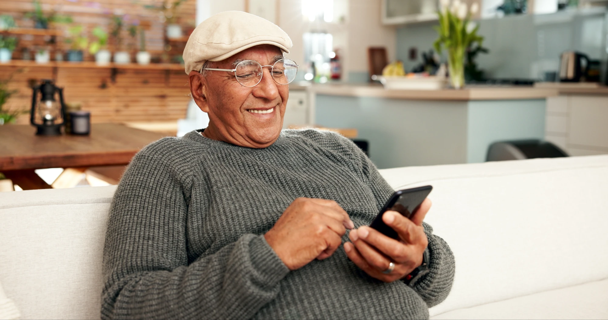 A smiling senior man using his phone comfortably at home