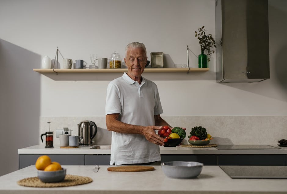 A senior man holding a bowl of fresh vegetables in a bright modern kitchen