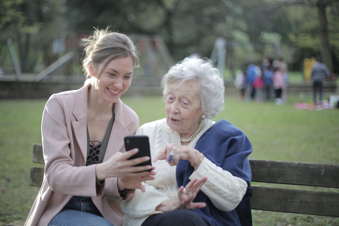An adult daughter and her aging mother smiling together over a phone