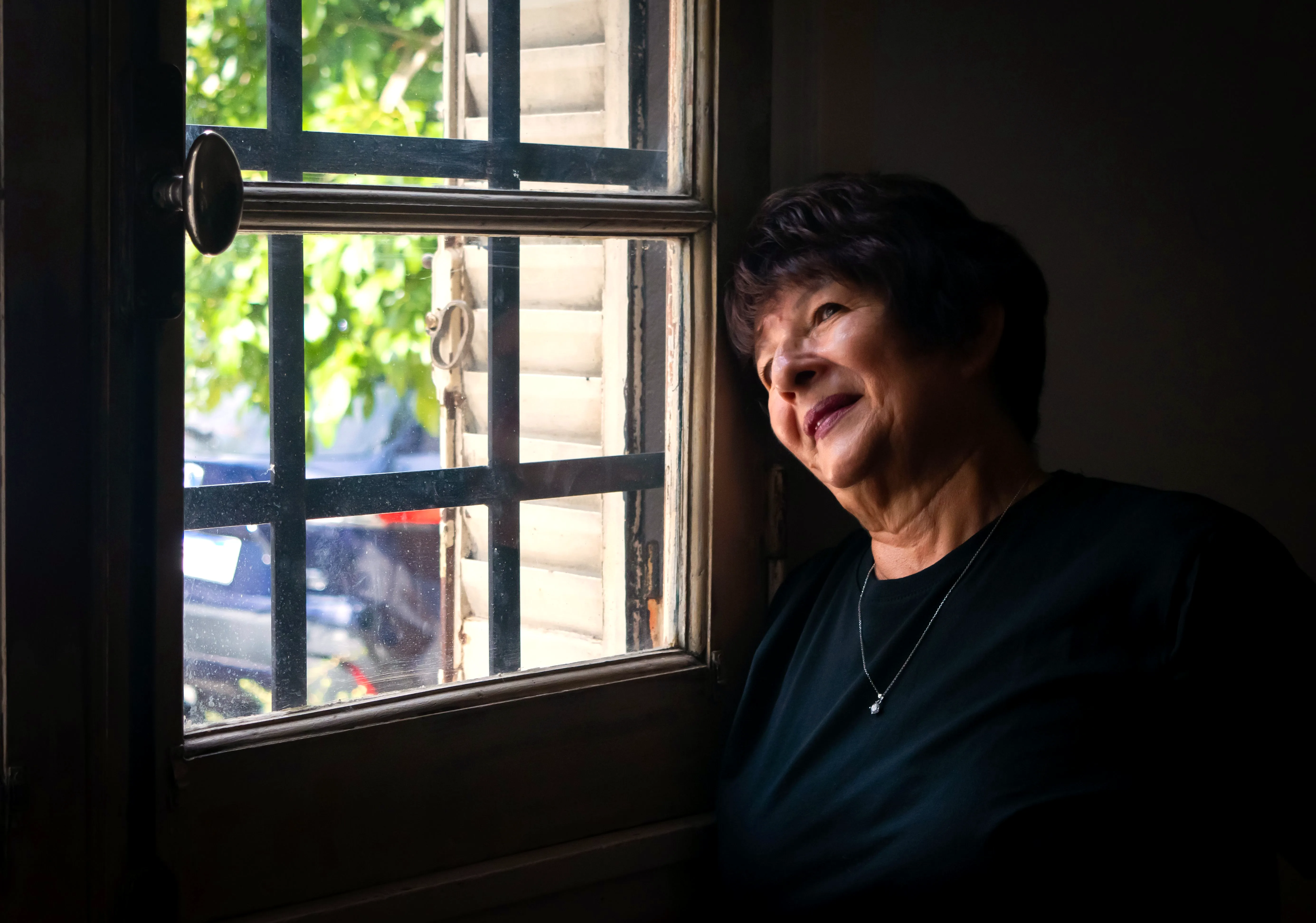 A senior woman gazing thoughtfully out a window